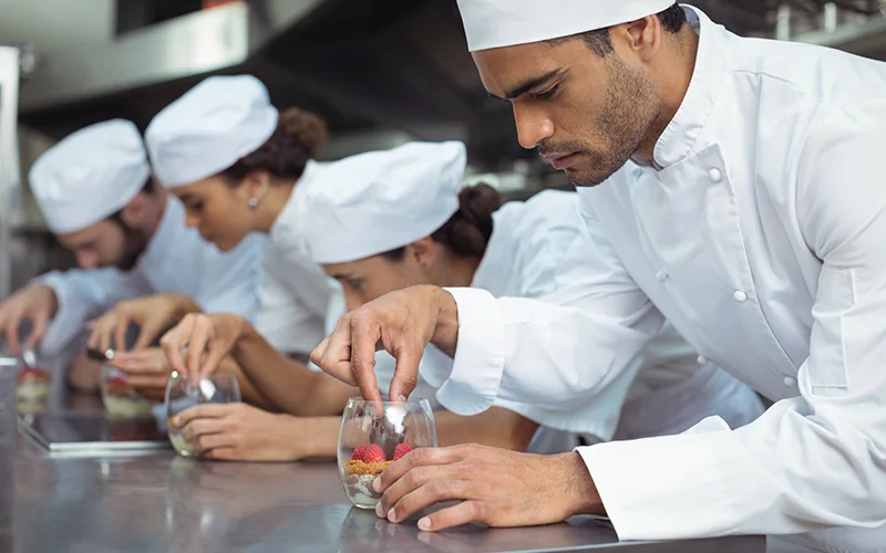 Chefs finishing dessert in glass at restaurant