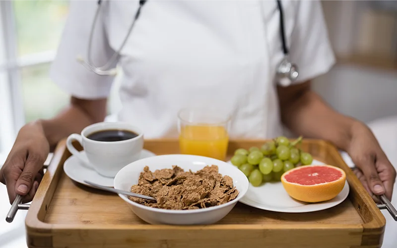 Mid section of nurse holding breakfast tray